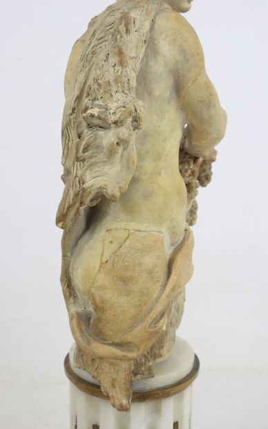 null A terracotta BACCHUS BUST resting on a marble base in the form of a fluted column,...