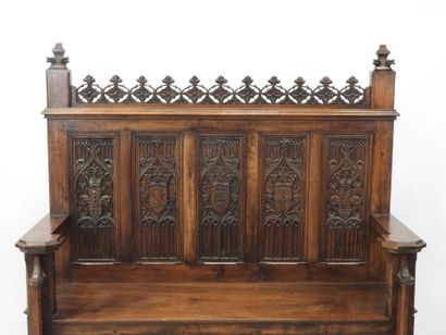 null Neo-Gothic style walnut bench with high straight back and heraldic decoration....