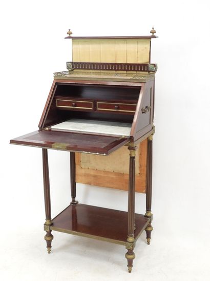 null A desk in mahogany and brass, the top decorated with a marble surrounded by...