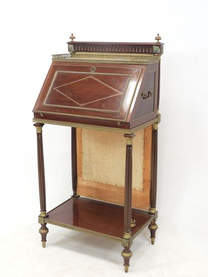 null A desk in mahogany and brass, the top decorated with a marble surrounded by...