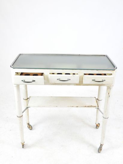 null DENTIST'S TABLE on castors in white lacquered metal opening to three drawers...