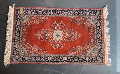 null Petit tapis persan à décor floral polychrome sur champ brique, 171x93 cm.