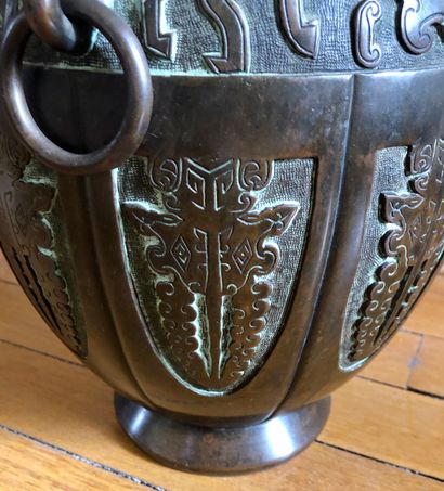 null Un vase ovoïde en bronze patiné à décor compartimenté et 3 anneaux suspendus...
