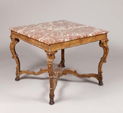 Maison JANSEN 
Table de milieu carrée en bois sculpté et doré, à plateau de marbre...