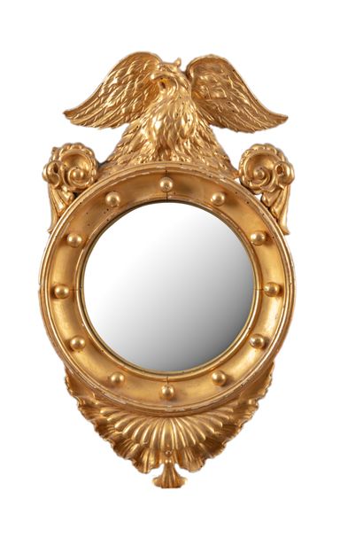 Miroir oval en bois doré surmonté d'un aigle...