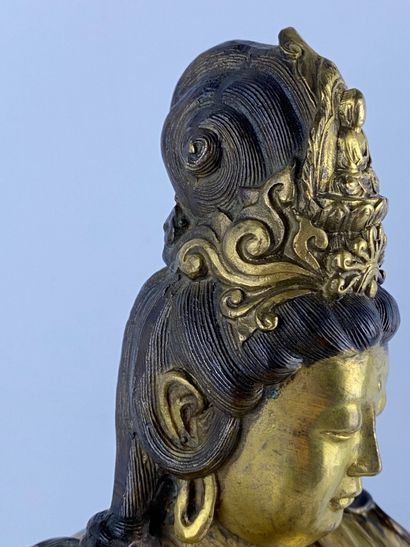  Guanyin en bronze doré Chine Représentée assise sur son rocher, la main droite posée...