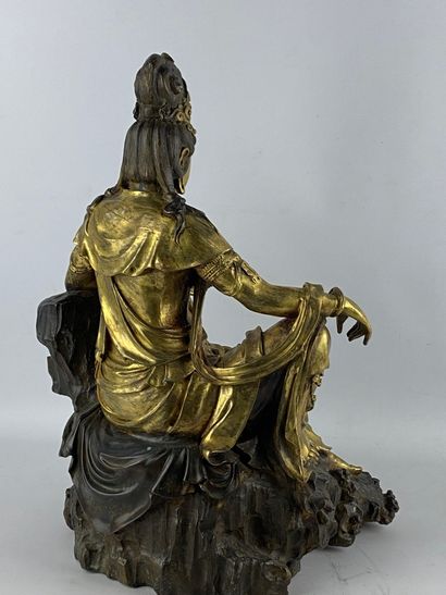  Guanyin en bronze doré Chine Représentée assise sur son rocher, la main droite posée...