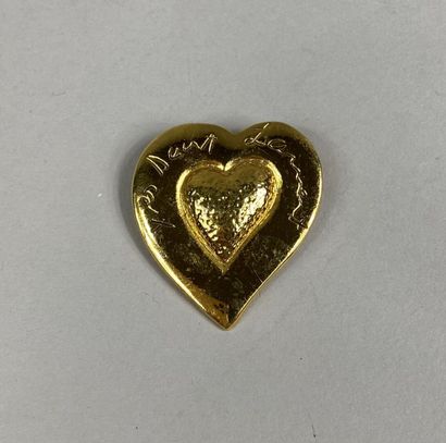  Yves SAINT LAURENT 
Broche en métal doré figurant un coeur, inscription "Yves Saint...