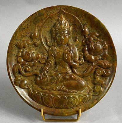  CHINA, 20th century 
Hard stone disc carved with the effigy of a deity on a lotiform...