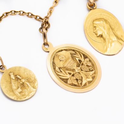 null Chaîne en or jaune 18 K (750) ornée de trois médailles religieuses, gravées....