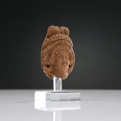null Female head with pierced ears. Her headdress, composed of two rows of sleeves,...