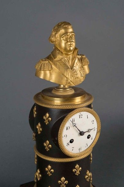 null Pendule borne figurant Louis XVIII en bronze patiné et doré, sur fond fleurdelisé....