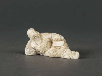 null JAPON Netsuké en ivoire sculpté et rehaussé de polychromie. Homme allongé, la...
