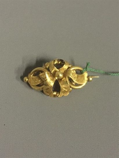 null Broche en or jaune 18 K (750) figurant un noeud stylisé avec perle d'or au centre....
