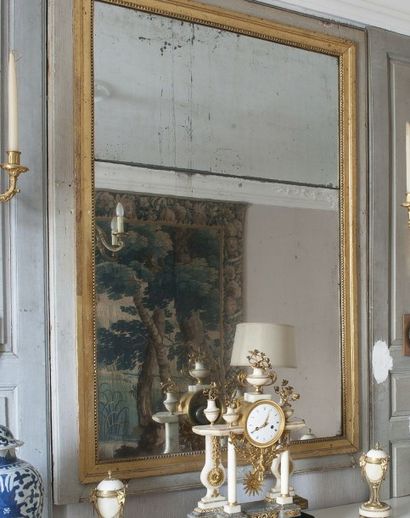 null TRUMEAU en bois laqué gris orné d'un miroir dans un encadrement doré à décor...