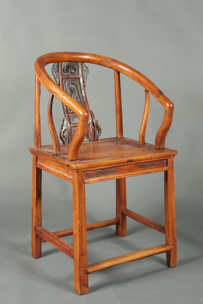 null China, 20th century. Blond wood armchair, with a low curved and openwork back...
