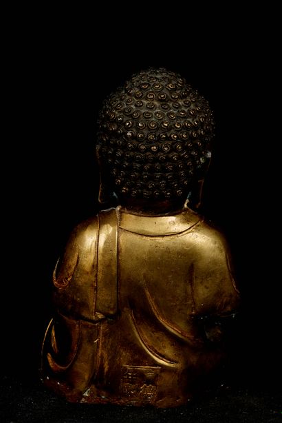 null Chine, XXème siècle. Bouddha assis en méditation tenant un modèle de temple...