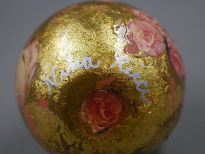 null attributed to NINA RICCI - Glass bottle with rose decorations on gold leaf background...