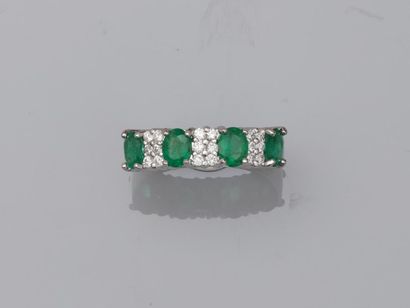 null 18k white gold line ring surmounted by four oval emeralds alternating with three...