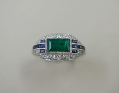 null Platinum ring surmounted by a rectangular emerald surrounded by lines of calibrated...