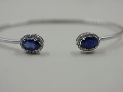 null 18k white gold open bracelet set with two oval sapphires surrounded by a line...