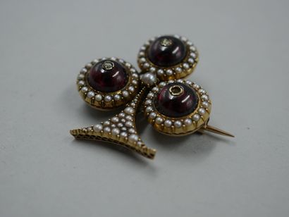 null Clover brooch in 18k yellow gold surmounted by three garnet cabochons centered...