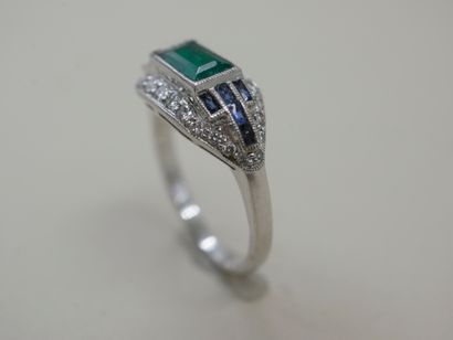 null Platinum ring surmounted by a rectangular emerald surrounded by lines of calibrated...