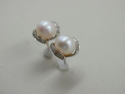 null A pair of 14k white gold earrings set with a cultured pearl and a line of diamonds....