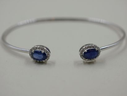 null 18k white gold open bracelet set with two oval sapphires surrounded by a line...
