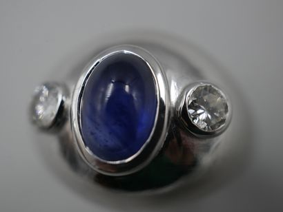 null Dome ring in 18k white gold set with an oval sapphire cabochon with two diamonds...