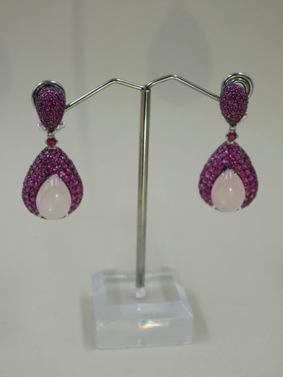 null Pair of 18k white gold earrings set with rubies and holding a pear-shaped cabochon...