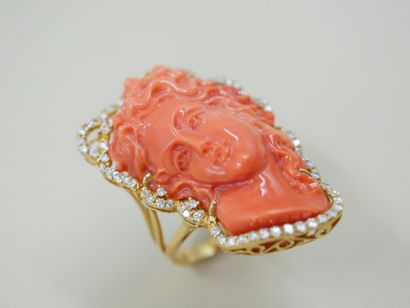 null 18k yellow gold ring surmounted by a woman's face with wavy coral hair surrounded...