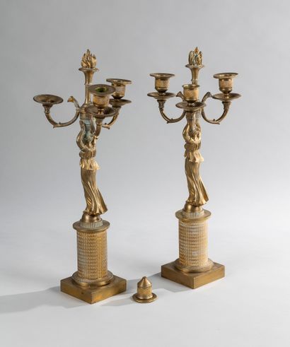 null A pair of three lights candelabra in gilt bronze representing a caryatid supporting...