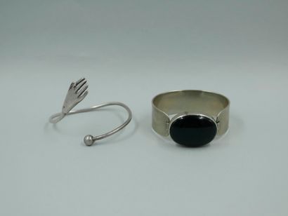 null Set of two metal bracelets, one featuring a hand, the other adorned with a black...