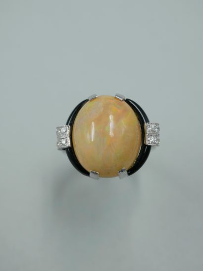null An Art Deco style 18K white gold ring set with a 7cts opal cabochon in an onyx...
