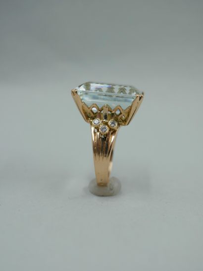 null An 18K yellow gold ring set with an emerald-cut aquamarine of about 15cts, supported...