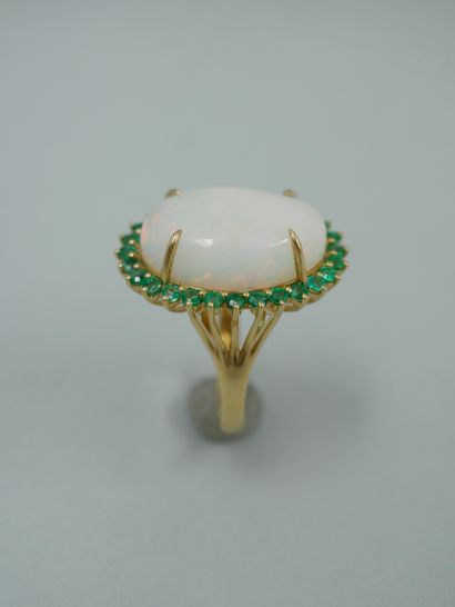 null An 18K yellow gold ring set with a 9ct oval opal in an emerald setting, the...