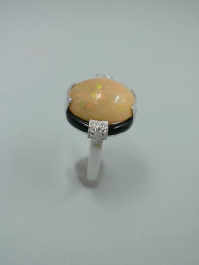 null An Art Deco style 18K white gold ring set with a 7cts opal cabochon in an onyx...