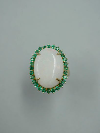 null An 18K yellow gold ring set with a 9ct oval opal in an emerald setting, the...