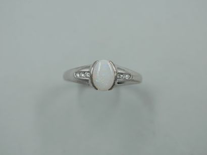 null A 9k white gold ring with an oval opal and a line of three diamonds on each...