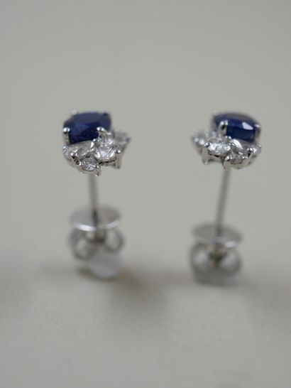 null A pair of 18k white gold earrings set with a sapphire weighing approximately...