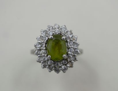 null An 18k white gold Pompadour ring with an olivine in a double border of diamonds....