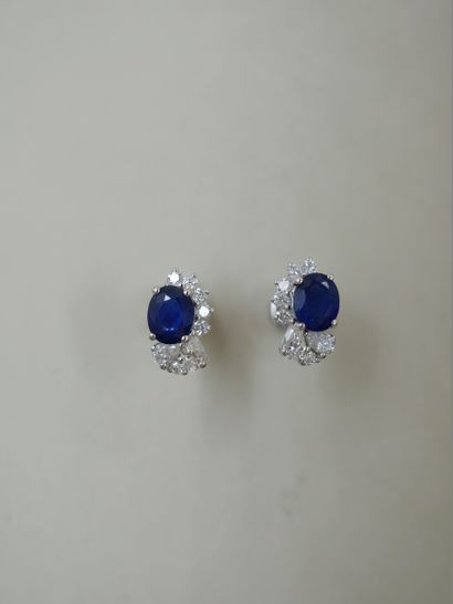 null A pair of 18k white gold earrings set with a sapphire weighing approximately...