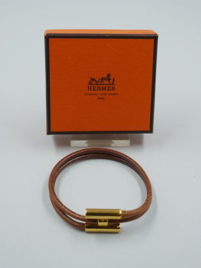 null HERMES Paris. Bracelet "Tournis" en cuir naturel marron et métal doré. Signé....