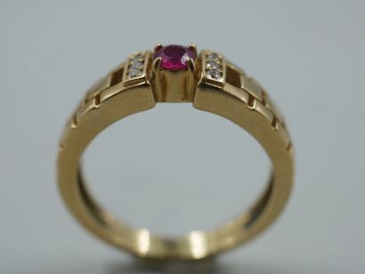 null 18k yellow gold ring, in the Cartier style, topped by a round ruby and two lines...