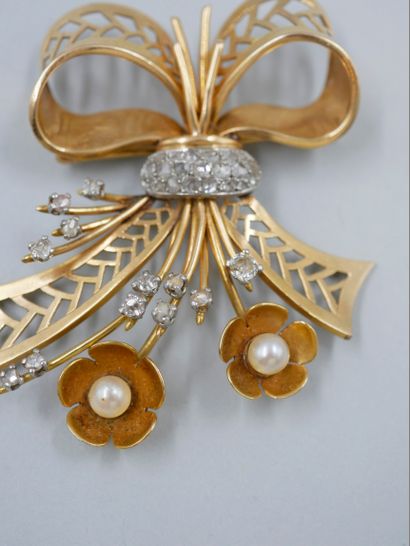 null Broche en or jaune 18K et platine figurant un nœud fleuri, agrémenté de perles...