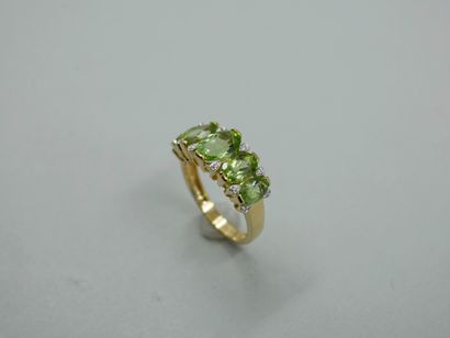 null Band ring in 18k yellow gold, decorated with oval peridots in fall punctuated...
