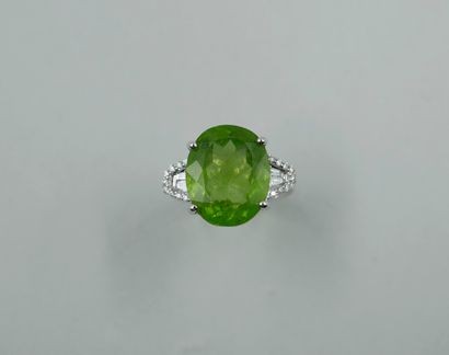 null 18k white gold ring set with an oval peridot of about 10 cts., surrounded by...