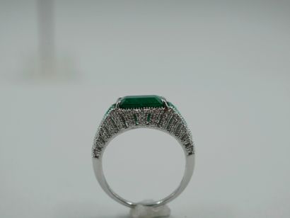 null 18k white gold ring set with a rectangular emerald of about 3 cts set claw flanked...