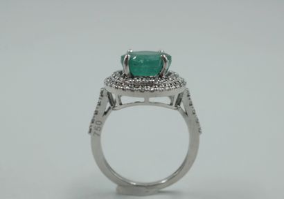 null 18k white gold ring set with a round emerald of about 4cts in a double surround...